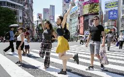 東京・渋谷駅前で、青信号でダッシュしてスクランブル交差点の中心に向かい、ポーズを決めて記念撮影する外国人=20日