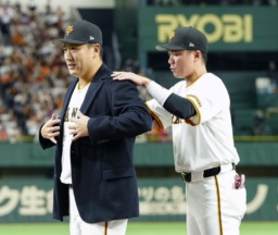 日米通算200勝達成を記念するセレモニーで、坂本勇人内野手(右)から受け取った名球会ブレザーを着る巨人・田中将大投手=1日、東京ドーム