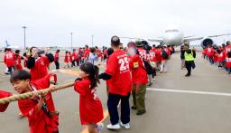 イベントで、綱でジェット機を引っ張る人たち=13日午前、成田空港