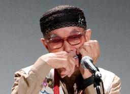 口琴の国際大会の開会式で演奏する奏者=24日午前、北海道釧路市の阿寒湖アイヌコタン