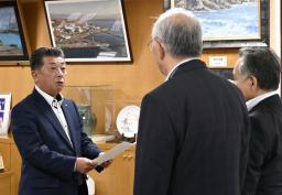北海道泊村議会の議長らから意見書を受け取る高橋鉄徳村長(左)=31日午前、北海道泊村