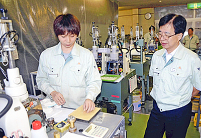 本宮工場で従業員の仕事を見守る石井社長（右）。「将来を見据えた人材育成が必要」と話す