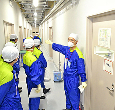 白い防護服に代わって導入された「構内専用服」。ナイロン素材で通気性が良い