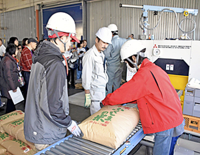ベルトコンベヤーで運ばれた袋を１袋ずつ検査する担当者＝６日、会津坂下町