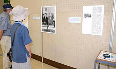 展示された記事や写真を鑑賞する来場者ら