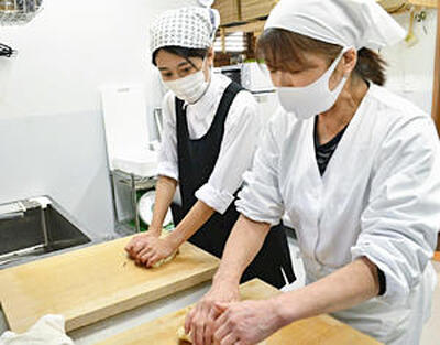 須田さん（右）の指導を受けながら、滑らかな舌触りを出すため白あんを練り上げる記者