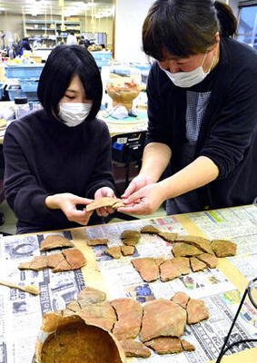 能登谷さん（右）と接合作業を行う記者。焼き色や模様を見ながら合わせていく