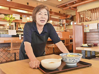 客席にランチメニューを運ぶ成子さん。震災は店の姿を大きく変えたが、成子さんのもてなしの心だけは変えることができなかった（吉田義広撮影）