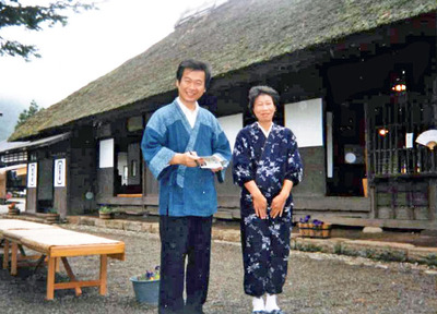 三澤屋の前で妻千恵子（右）と私。店をそば屋に切り替え、看板メニューを作ろうと試行錯誤の日々が続いていた。千恵子は温かく観光客を迎え入れ癒やしを届ける環境をつくってくれた