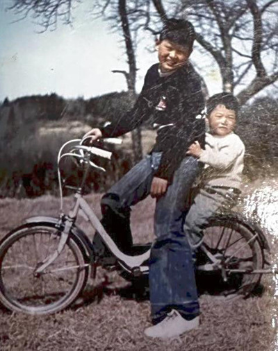 ９歳上の兄信二（左）と自転車に乗る幼い私。兄の背中を見て、バイクに憧れを抱いた