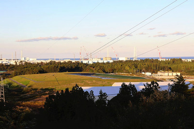 中間貯蔵施設内のあちこちに積まれた除去土壌の山。奥に見えるのは東京電力福島第１原発＝大熊町
