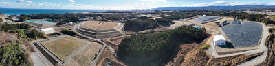 県内の除染で出た土壌などが運び込まれた中間貯蔵施設。２、３段が重なる「山」の一つ一つに大量の土壌が保管され、高さは最大１５メートルに及ぶ。中央奥は東京電力福島第１原発＝昨年１２月、双葉町（ドローンで撮影した写真６枚をパノラマ合成）