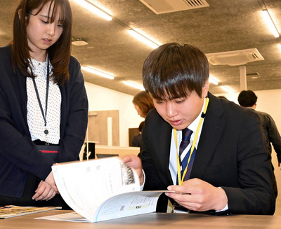 先輩から説明を受ける木幡穣清さん（右）。「住民同士のつながりが強く、温かかった町をもう一度見たい」と語る＝双葉町役場