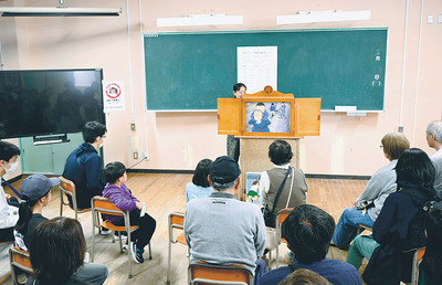紙芝居を読み聞かせる八島代表と聞き入る来館者