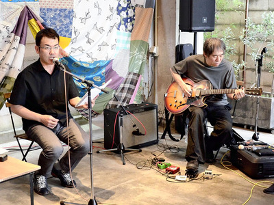 大友さんのギターと和合さんの朗読が共演した即興ライブ。背景はプロジェクトで作った「福島大風呂敷」の一部