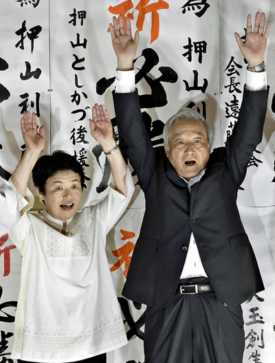 ４選を飾り、万歳する押山氏。左は妻厚子さん