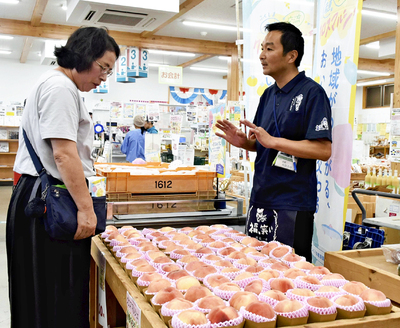 国見町産のモモや取り組みを紹介する矢吹店長（右） ＝あだたらの里直売所