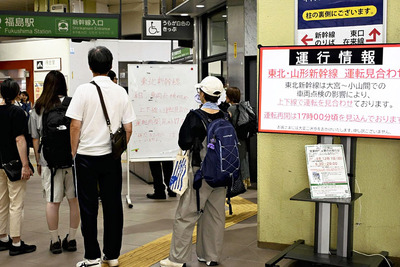 東北新幹線の運転見合わせを知らせる案内板を見つめる利用者＝２４日午後４時２０分ごろ、ＪＲ福島駅西口