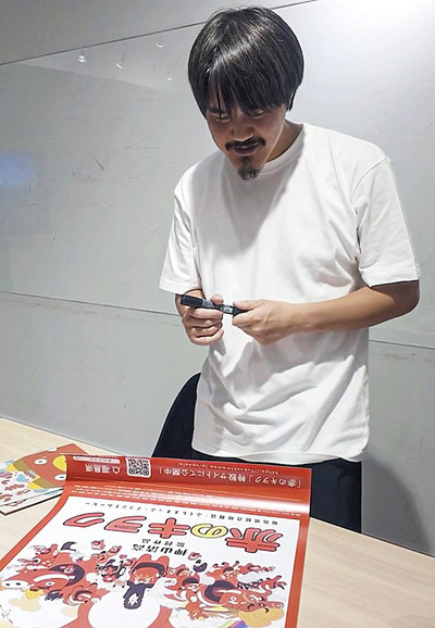 「赤のキヲク」のポスターにサインを入れる押山監督