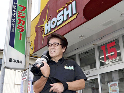 愛用のカメラを手にする私。星写真館の３代目として奔走し、今は学校行事を主に撮影している