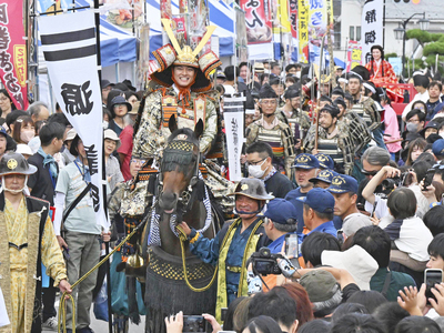 歴史絵巻を繰り広げた「義経公行列」。義経に扮した中山優馬さん（中央馬上）と静御前を演じた優希美青さん（右奥）が沿道の声援に応えた＝２３日午後、国見町・藤田商店街