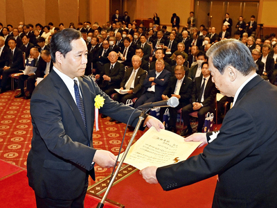 今泉副会頭から産業特別功労賞表彰を受ける丹治元会頭の親族丹治滋さん（左）