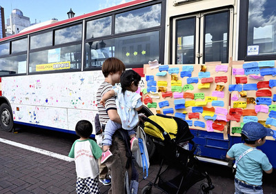 「お絵かきバス」に折り紙を貼り付ける来場者