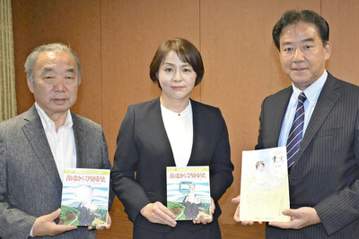 復刊した絵本を手にする橋本代表（中央）と本名さん（左）、篠崎さん