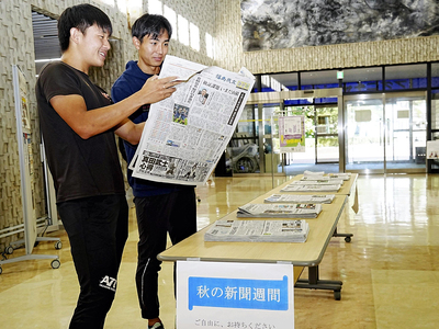 新聞を手に取り記事を読む福島大生