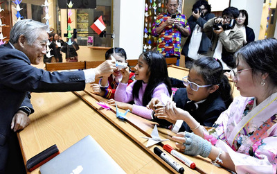 マチュピチュ村の日本語教室で現地の子どもたちと折り紙で触れ合う押山村長（左）