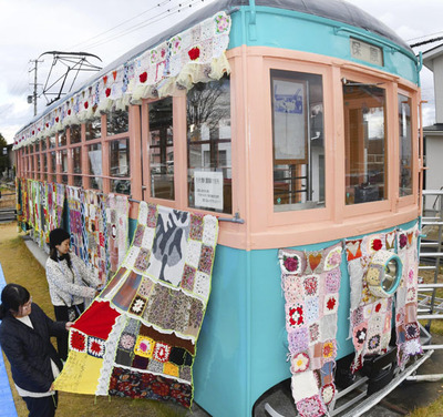 カラフルな手作りニットで彩られる路面電車＝２１日、伊達市保原町・チンチン電車前広場