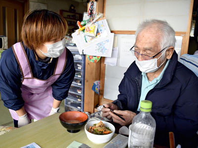 食事の味見をする利用者の男性（右）。女性ヘルパーは「利用者自身の生活をサポートしているという実感がやりがいになる」と話す＝天栄村