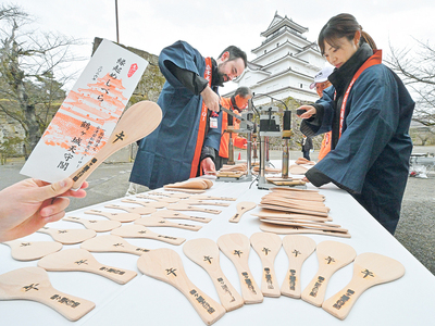 縁起物「飯べら」に焼き印を押していく関係者ら ＝３日午前、会津若松市・鶴ケ城
