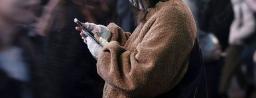 　東京・渋谷のスクランブル交差点でスマートフォンを手にする人＝２月