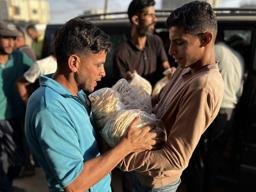 　２２日、パレスチナ自治区ガザで食料配給のパンを受け取る人々（ゲッティ＝共同）