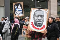 　２５日、ニューヨークでジョージ・フロイドさんを描いたプラカードを掲げるデモ行進の参加者（共同）