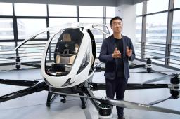 　２人搭乗可能な「空飛ぶクルマ」の前に立つ億航智能の開発責任者、賀天星氏＝３月、中国広東省広州市（共同）
