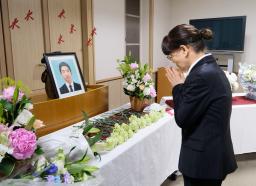 　市川大輔さんの遺影に向かい手を合わせる母正子さん＝３日午後、東京都港区