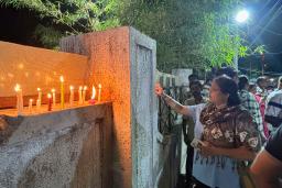 　旅客機が墜落した現場近くで、犠牲者を悼みろうそくに火をともす女性＝１３日、インド西部アーメダバード（共同）