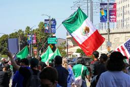 　１１日、米ロサンゼルスで、メキシコ国旗を掲げる抗議デモ参加者ら（共同）