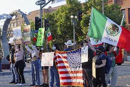 　米国やメキシコの国旗を掲げ、移民取り締まりに抗議する人々＝８日、ロサンゼルス