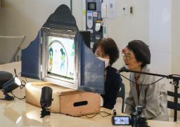 　平和活動４０年のパネル展に合わせ、紙芝居を披露する三田村静子さん（右）＝１６日午後、長崎市