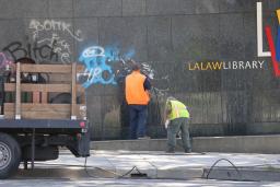 　１６日、米ロサンゼルスで、抗議デモ参加者らによる落書きの除去作業をする人（共同）