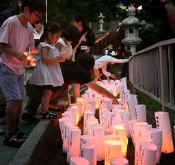 　戦死した特攻隊員を悼む集いで、灯籠に明かりをともす子どもたち＝２１日午後、鹿児島県鹿屋市