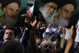 　イラン最高指導者ハメネイ師（中央上）や革命指導者の故ホメイニ師のポスターを掲げ、米軍の核施設攻撃に抗議する人たち＝２２日、テヘラン（ＡＰ＝共同）