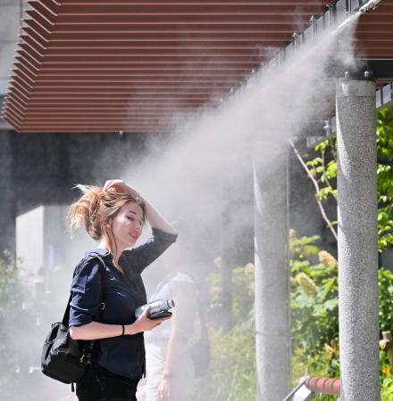 　全国的に気温が上昇した２８日、真夏のような暑さとなった東京・銀座でミストを浴び涼む女性