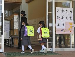 　「これから仲よくしよう」のボードが掲げられた石川県能登町立柳田小に入る輪島市立町野小の児童ら＝昨年１０月、能登町