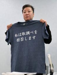 　勾留中の男性が着ていた「私は取調べを拒否します」と記されたＴシャツを手にする松本亜土弁護士＝１日午前、大阪市北区