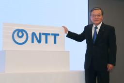 　「ＮＴＴ」への社名変更に伴う式典で、ロゴと写真に納まる島田明社長＝１日午前、東京都内