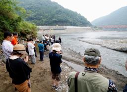 　２０２０年７月の豪雨から５年となり、氾濫で多くの被害をもたらした球磨川（奥）周辺で黙とうする人たち＝４日午前、熊本県八代市